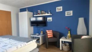 奥斯赛拜-塞林Ferienwohnung Neuensien的一间卧室设有蓝色的墙壁、一张床和一把椅子