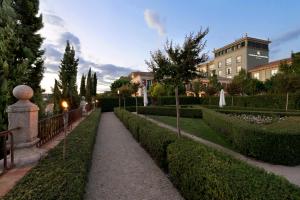 托莱多欧洲之星布埃纳维斯塔宫酒店的公园里一条有灌木丛和建筑物的走道