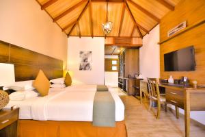 Thinadhoo马尔代夫羽毛旅馆的一间带大床的卧室和一间餐厅
