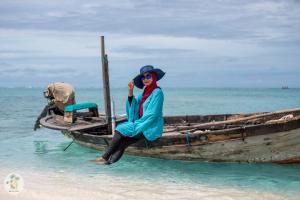 FeridhooShifa Lodge Maldives的坐在海滩上船上的女人