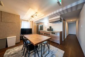 神户HOTEL er.的厨房以及带木桌和椅子的用餐室。
