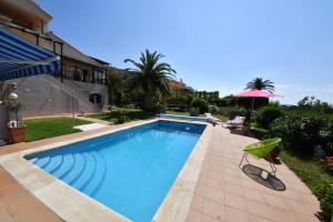 PauSuite & Spa Panoramic Olivars的一座房子旁带遮阳伞的游泳池