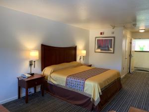 南旧金山机场旅馆的一间卧室配有一张床和一张带两盏灯的桌子。