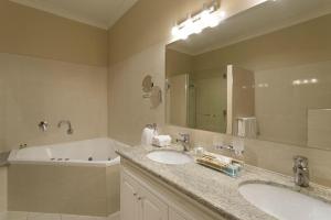 朗塞斯顿The Grand Hotel Launceston (Formerly Clarion Hotel)的浴室配有2个盥洗盆、浴缸和大镜子
