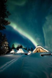 萨利色尔卡Wilderness Hotel Muotka & Igloos的一群雪中帐篷,天空中有一根彩虹