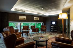 特伦托特兰托大酒店的一间设有椅子和桌子的等候室以及一台电视