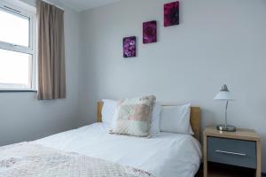 班多伦Marine Court的一间卧室配有一张带白色床单的床和一扇窗户。