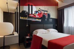 马拉内罗Hotel Maranello Village的卧室配有一张床铺,墙上挂着赛车