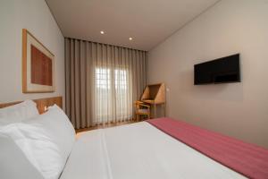 维塞乌Montebelo Principe Perfeito Viseu Garden Hotel的卧室配有一张大白色床和平面电视