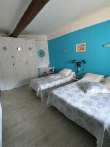 阿普特Hôtel-restaurant le Palais的蓝色墙壁客房的两张床
