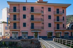 莫内利亚天堂公寓式酒店的前面有走道的粉红色建筑