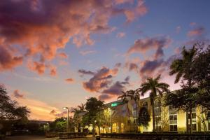 黎明城La Quinta Inn & Suites by Wyndham Sunrise的棕榈树和云天的建筑