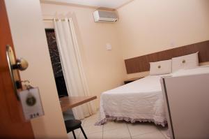 Santa BárbaraImperial Hotel的配有一张床、一张书桌和一扇窗户的酒店客房