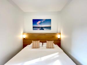 奈扬海滩Pensiri House - SHA Extra Plus的卧室配有一张白色床,墙上挂着一幅画
