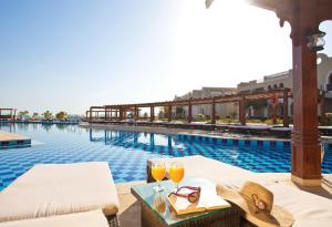 沙姆沙伊赫Sunrise Arabian Beach Resort的一座酒店游泳池,提供两杯橙汁