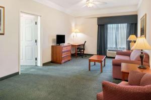 迈尔斯堡La Quinta Inn and Suites Fort Myers I-75的带沙发和书桌的酒店客房
