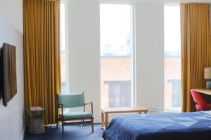达拉姆达勒姆酒店的一间卧室配有一张床、一把椅子和窗户。
