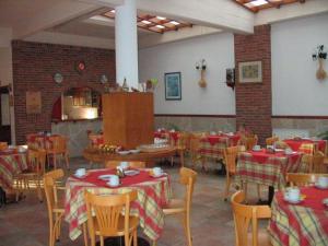 格塞尔镇蓝晶酒店的餐厅设有桌椅,配有红色和白色的桌布