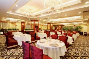 广州广州嘉逸豪庭酒店的餐厅设有白色的桌椅和吊灯。