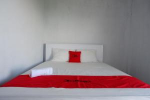 TenjoRedDoorz near Lokawisata Baturaden 2的一张白色的床,上面有红色枕头