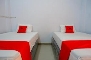 TenjoRedDoorz near Lokawisata Baturaden 2的客房内的两张床和红色枕头