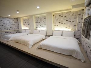 新竹合悅都會商旅 Heyue HOTEL的两张睡床坐在一个房间里长凳上