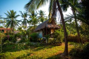 贡布Retro Kampot Guesthouse的茅草屋顶和棕榈树的小小屋