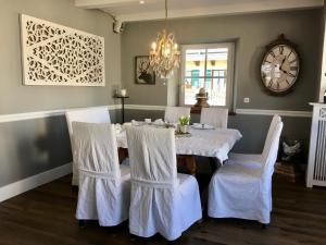 里姆斯廷格太阳酒店的用餐室配有带白色椅子的桌子和时钟