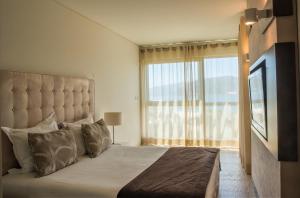 特罗亚Troia Residence by The Editory - Apartamentos Praia的一间卧室设有一张大床和大窗户