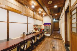 松本Couch Potato Hostel的餐厅里设有长长的酒吧,铺有木地板