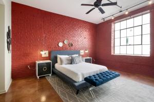 新奥尔良LiivUP Warehouse Apartments的红砖卧室配有一张床和蓝色的搁脚凳
