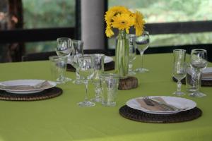 凯里凯里伍德兰兹汽车旅馆的绿桌,带玻璃杯和盘子,花瓶带黄花