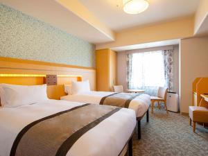 神户Hotel Monterey Kobe的酒店客房设有三张床和窗户。