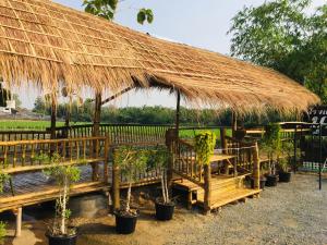 北碧布萨拉库姆度假酒店的一个大草屋,长凳和盆栽植物