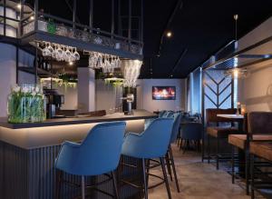 亚琛Best Western Plus Hotel Regence的一间设有蓝色凳子的餐厅内的酒吧