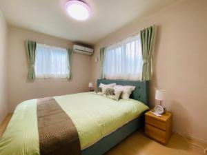 福冈福恵館的一间卧室配有一张带绿色床头板和窗户的床。