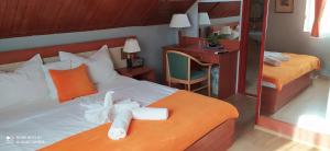 希欧福克Hermina Panzió的一间卧室配有两张带橙色枕头的床和一张书桌