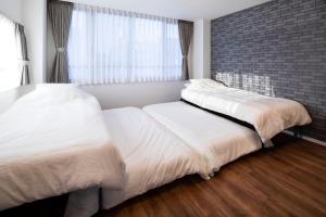 东京HOTEL LITTLE BIRD OKU-ASAKUSA / Vacation STAY 79448的卧室设有2张床,设有砖墙