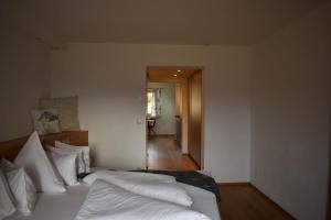 奥布施泰希Bucherhof的一间卧室配有一张带白色床单的床和走廊。