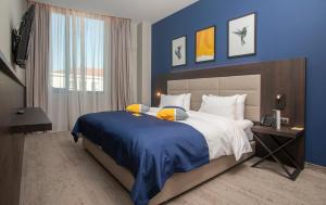 波德戈里察voco - Podgorica, an IHG Hotel的一间卧室设有一张蓝色墙壁的大床