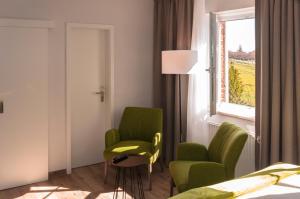 Sulsdorf auf FehmarnLindenhof Hotel Garni的一间卧室设有两张绿色椅子和窗户