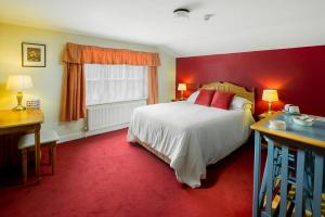 哈罗盖特The Queens Head Kettlesing的一间卧室设有一张床和红色的墙壁