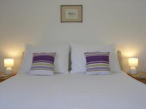 巴斯卡Apartments GORDANA Baska for relaxing holidays的一张带两个枕头和两盏灯的白色床