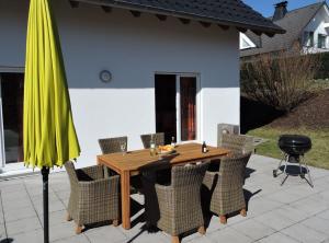 温特贝格Ferienhaus - Haus Winterberg的一张带椅子的木桌和黄色雨伞