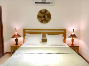 巴拉格兰德Carapitangui Pousada的一间卧室配有一张带两盏灯和闹钟的床。