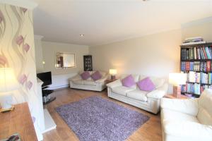 MarpleSpacious bungalow/private garden-sleeps up to 6的客厅配有2张白色沙发和紫色枕头
