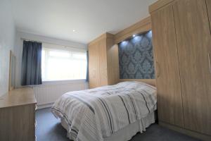 MarpleSpacious bungalow/private garden-sleeps up to 6的一间卧室配有一张带木制床头板的床和窗户。