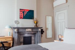 马斯特里赫特Maison Haas Hustinx & Spa的卧室设有壁炉,墙上挂有绘画作品