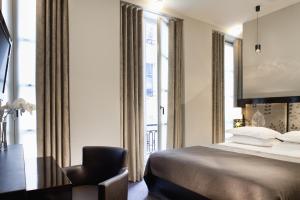 巴黎Hôtel Caron le Marais的一间卧室配有一张床、一把椅子和一个大窗户
