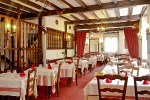 阿斯帕朗Relais Des Tilleuls的一间设有白色桌椅和红色窗帘的餐厅